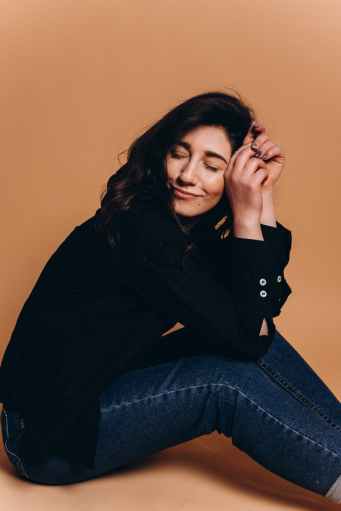 happy young woman sitting on floor in studio with closed eyes